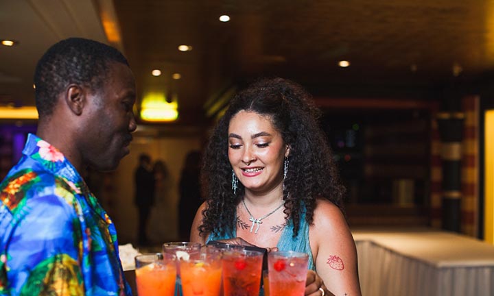 Joyful Welcome Drinks on Your Personalized Sailaway Wedding Cruise A smiling woman onboard a cruise ship selecting colorful welcome drinks served by a crew member during a sailaway celebration.